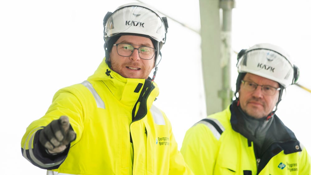 Två kollegor i hjälm och varselkläder pratar med varandra.