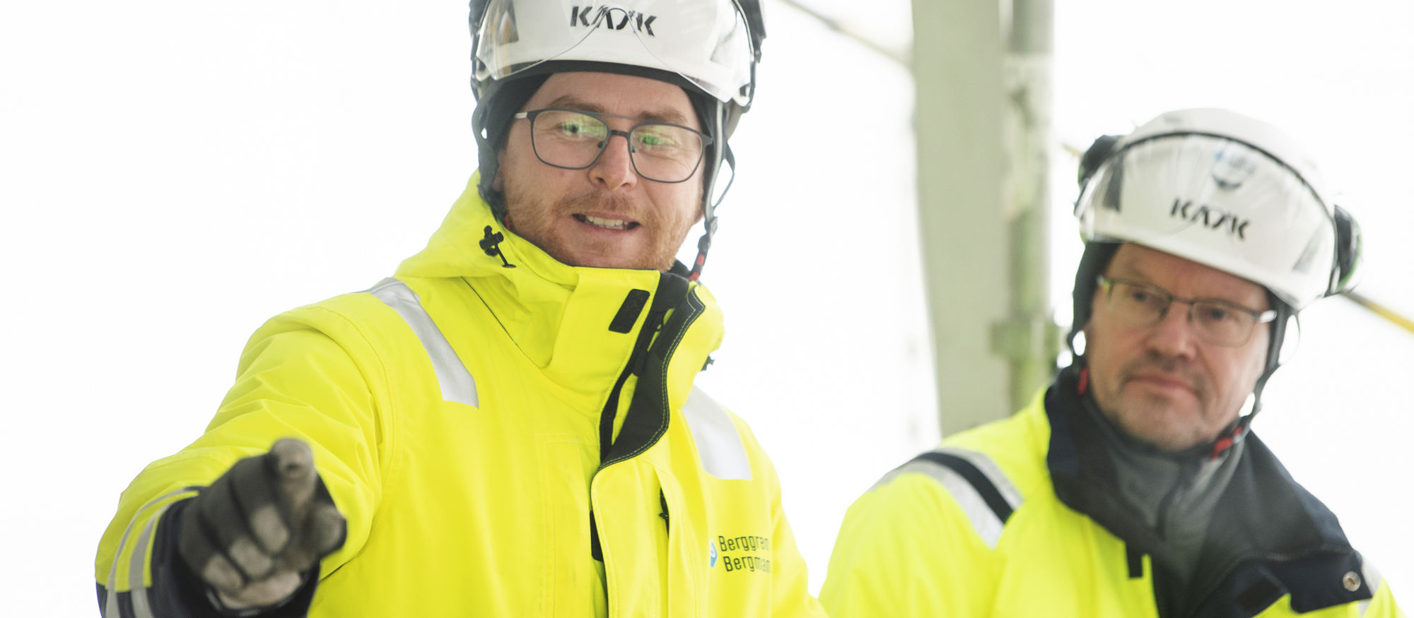 Två kollegor i hjälm och varselkläder pratar med varandra.