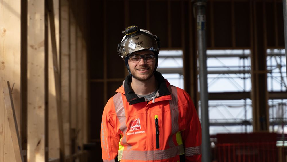 Foto av Veidekkes medarbetare William Dahlström. Står leende i varselkläder och hjälm.