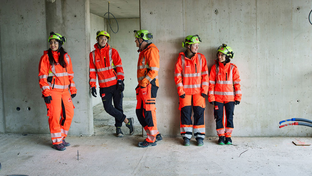 Ung kvinnlig byggarbetare i skyddsutrustning, Stella, står vid grönlysande laserpekare inomhus i ett nybuggnadsprojekt.