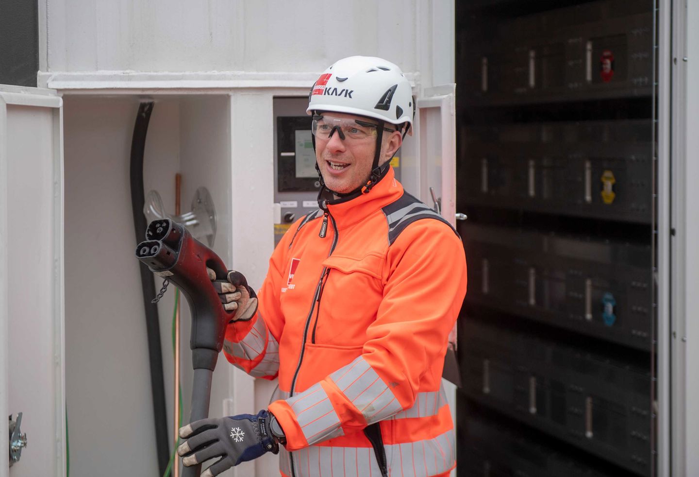 Man i varselkläder framför en laddstation 