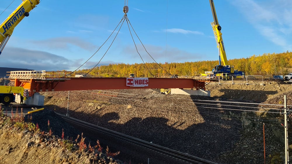 Bild över när kran lyfter bro på plats över en järnväg.