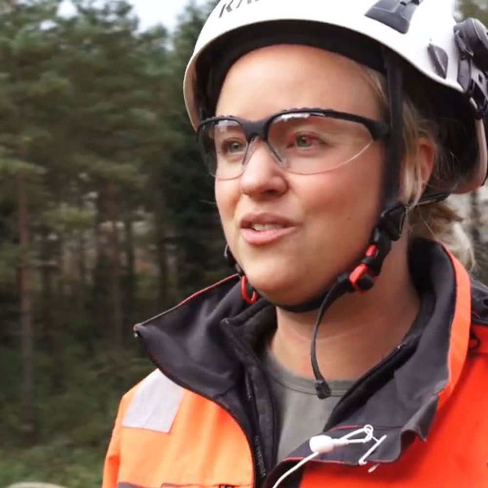 Foto av Veidekkes medarbetare Johanna Axelsson. Står leende i varselkläder och hjälm.