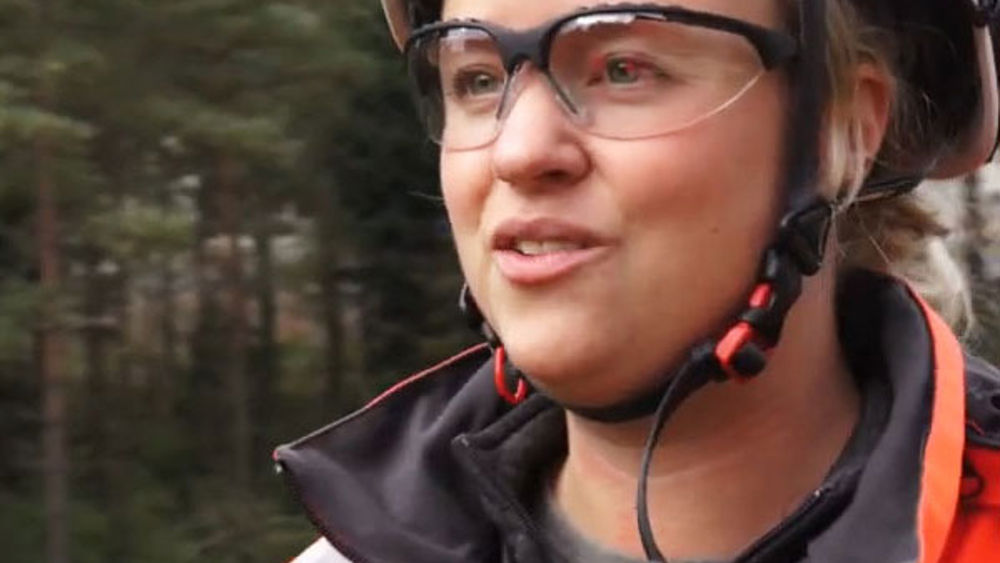 Foto av Veidekkes medarbetare Johanna Axelsson. Står leende i varselkläder och hjälm.