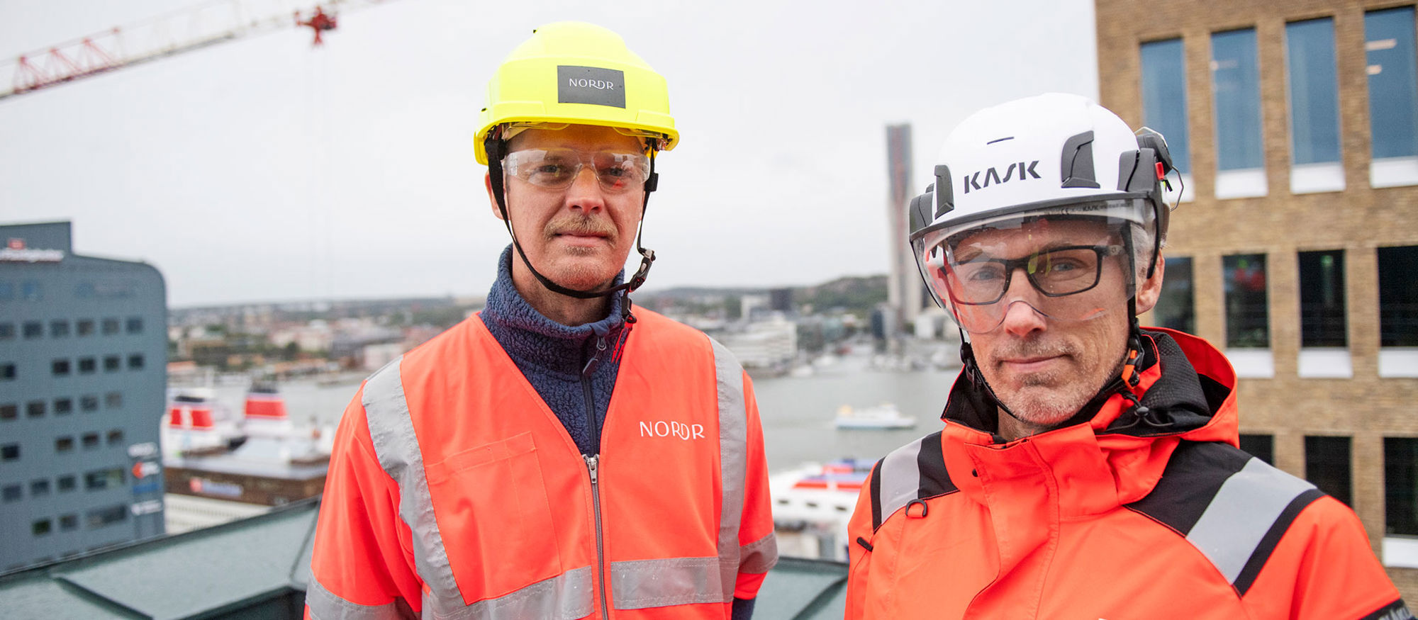 Foto av två män som står i bygghjälmar och varseljackor.