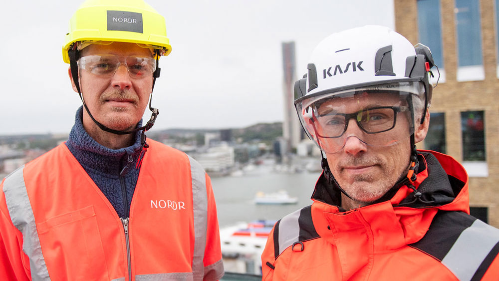 Foto av två män som står i bygghjälmar och varseljackor.