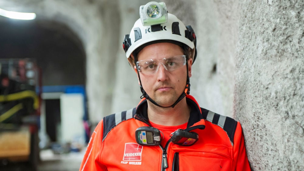 En medarbetare på Veidekke klädd i varsel med hjälm inne i ett bergrum.