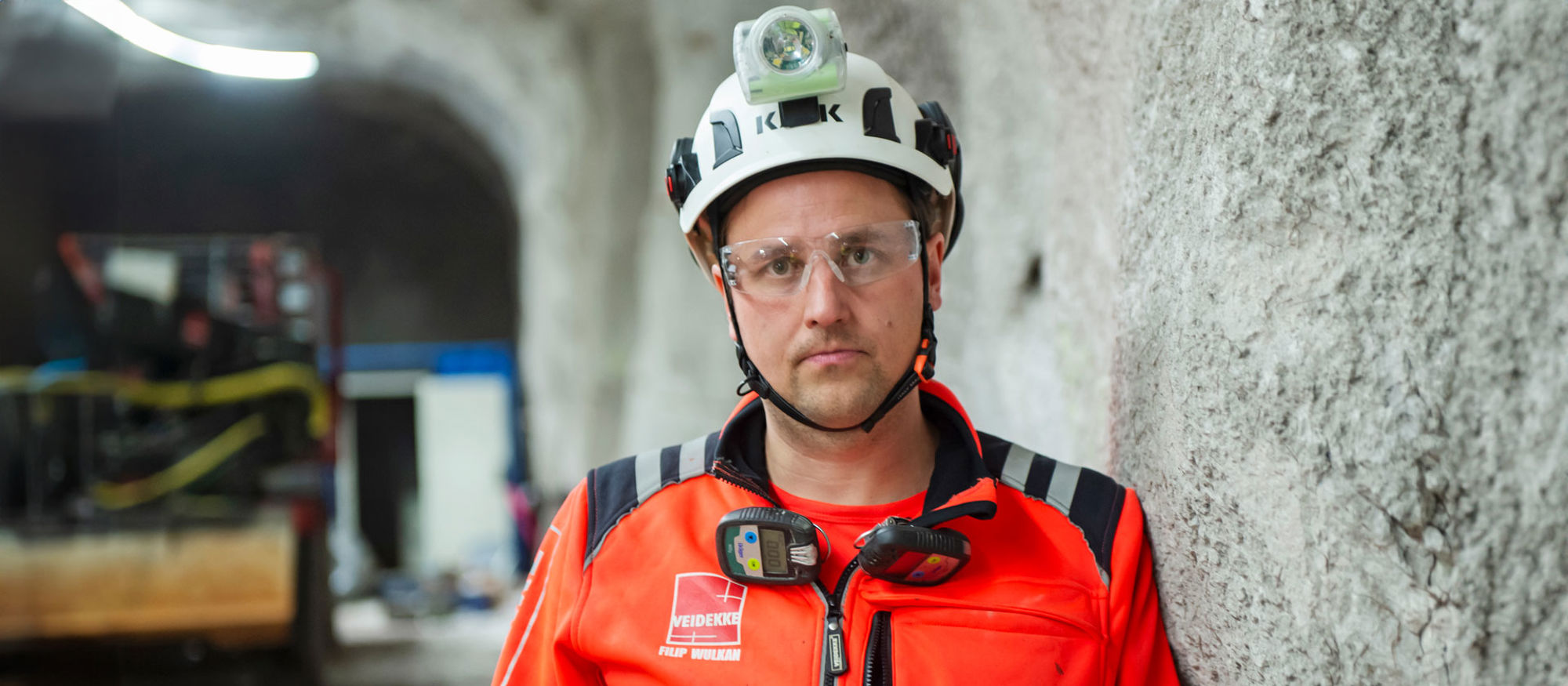 En medarbetare på Veidekke klädd i varsel med hjälm inne i ett bergrum.