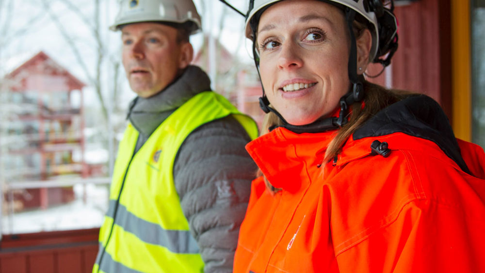 Röda lägenhetshus i trä i vintervitt landskap.