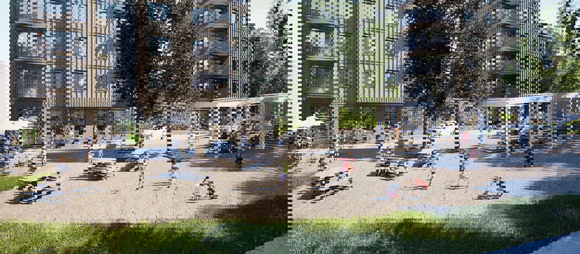 Gruslagd innergård där barn leker. I bakgrunden ett grått flerfamiljshus - Brf Månstenen