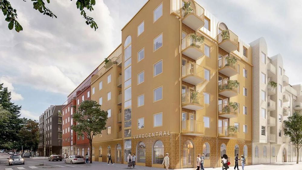 Kvarteret Bollen. Hörnet av en sexvåningsbyggnad i gul puts vid stadsgata med vårdcentral i bottenplan 