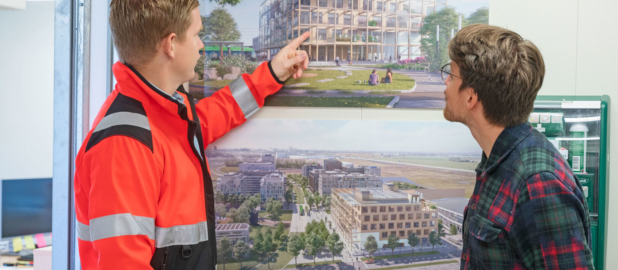 Två personer tittar på ett foto som hänger på en vägg, fotot föreställer en byggnad.