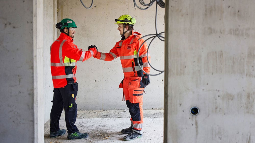 Två personer skakar hand på en byggarbetsplats.