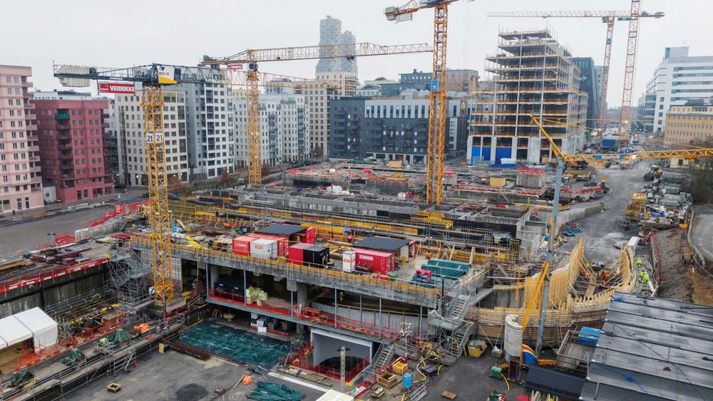 Flygbild över stor betongstruktur i stadsmiljö med flera kranar - Bellmansgaraget under uppbyggnad