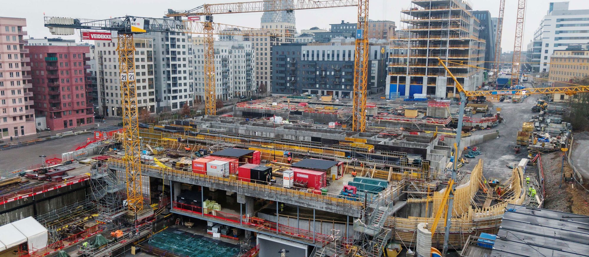 Flygbild över stor betongstruktur i stadsmiljö med flera kranar - Bellmansgaraget under uppbyggnad