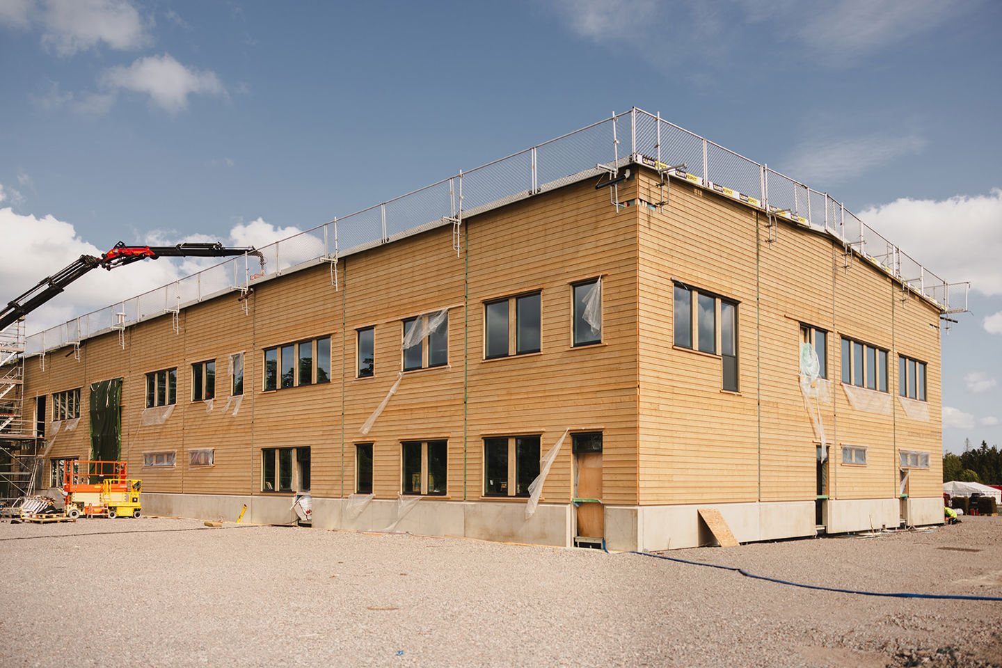 Större industribyggnad i trä under pågående bygge. Här är väggarna på plats och en kran sträcker sig över taket