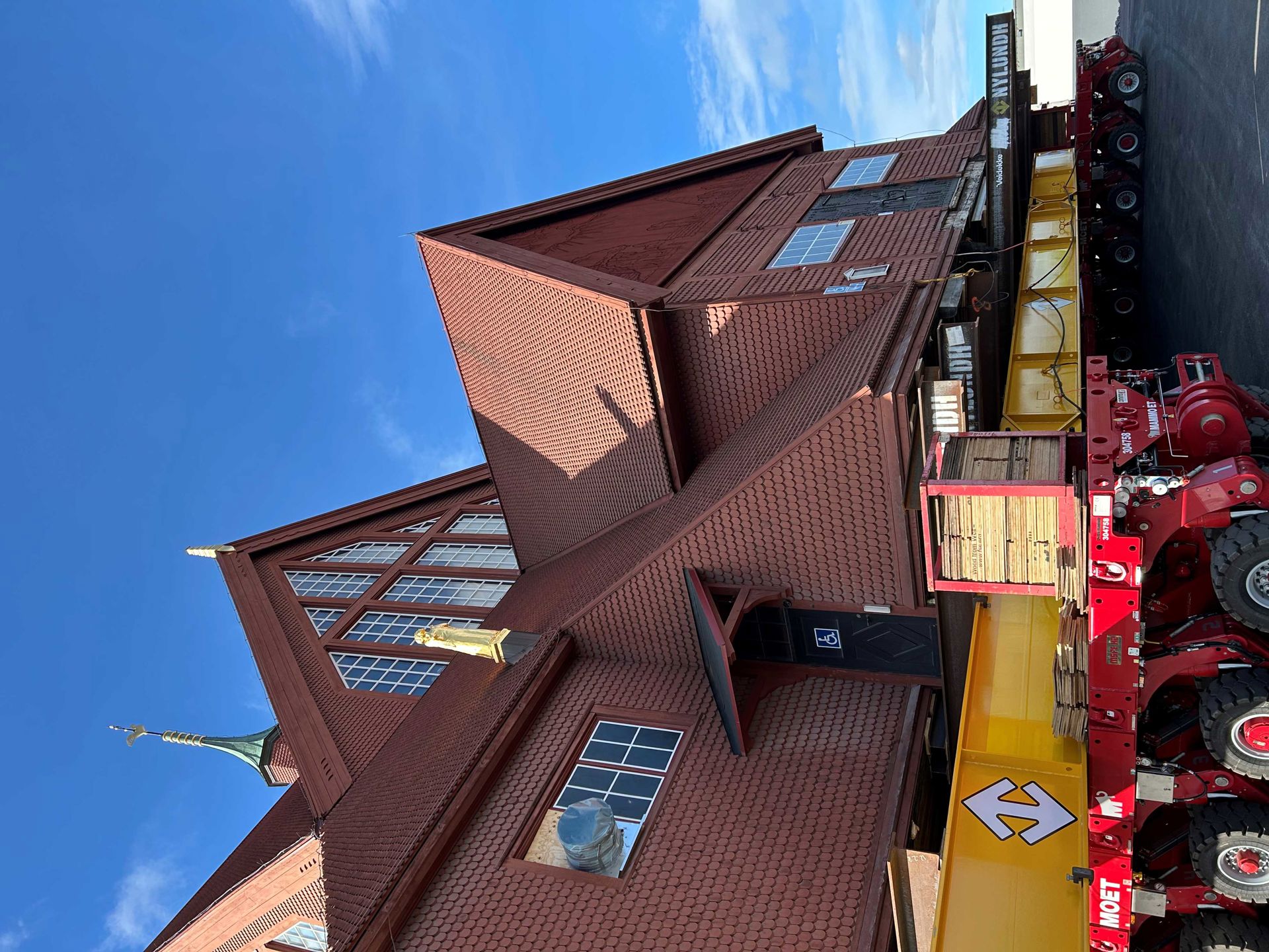 Kiruna kyrka, en stor röd träbyggnad, står på balkar på trailers i gult