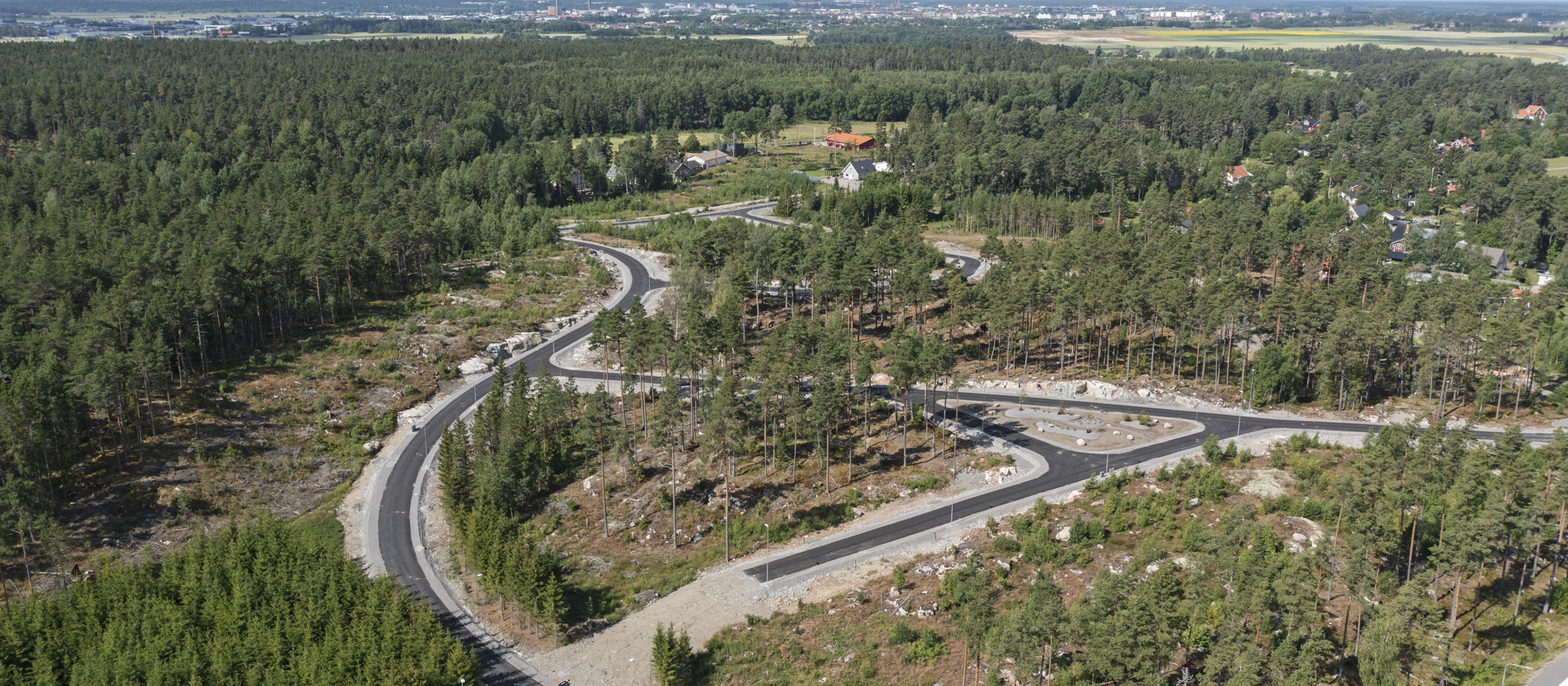 Skölsta. Drönarbild över grönt område med nyanlagda gator och vägar. 