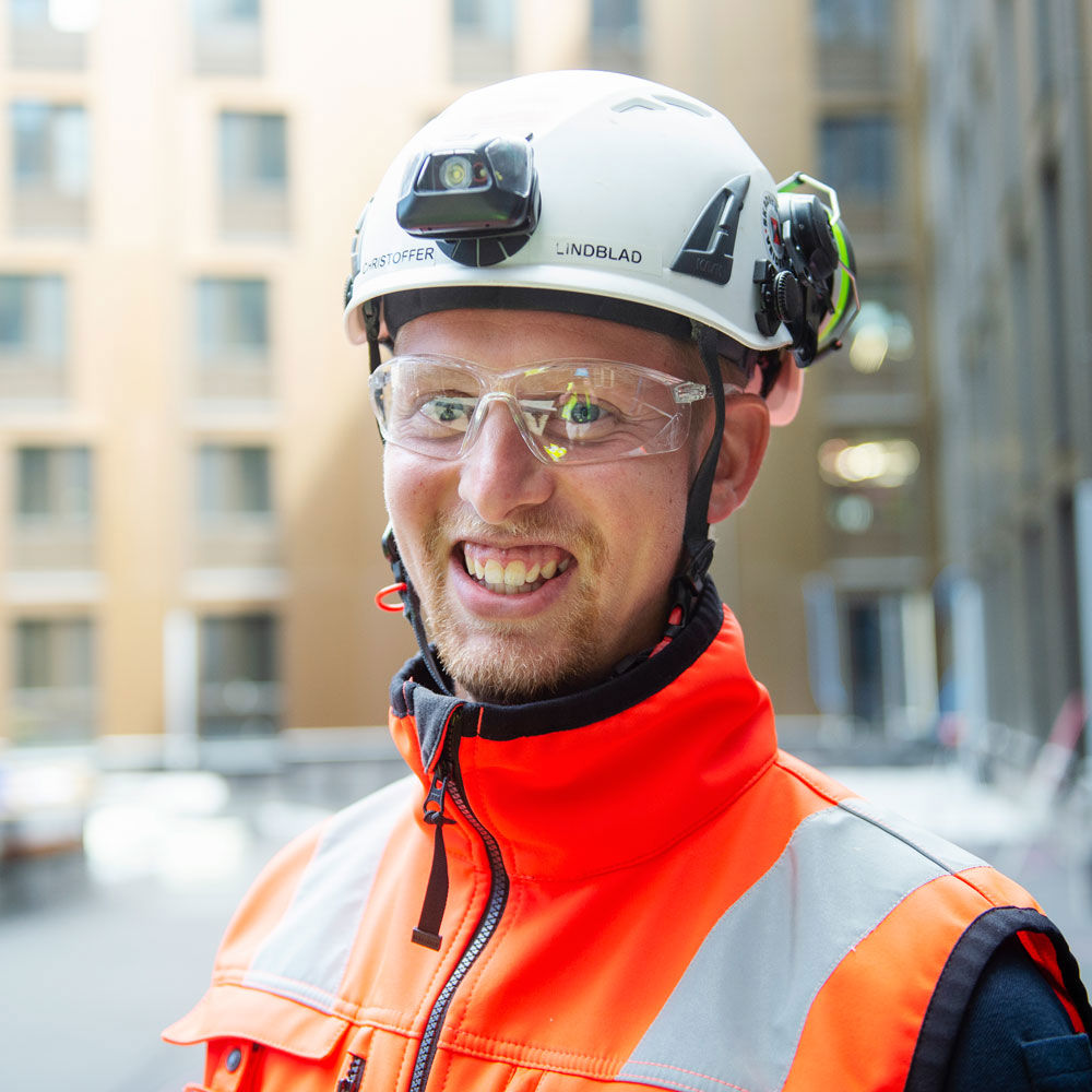 Foto av Veidekkes medarbetare Christoffer Lindblad. Står leende i varselkläder och hjälm.