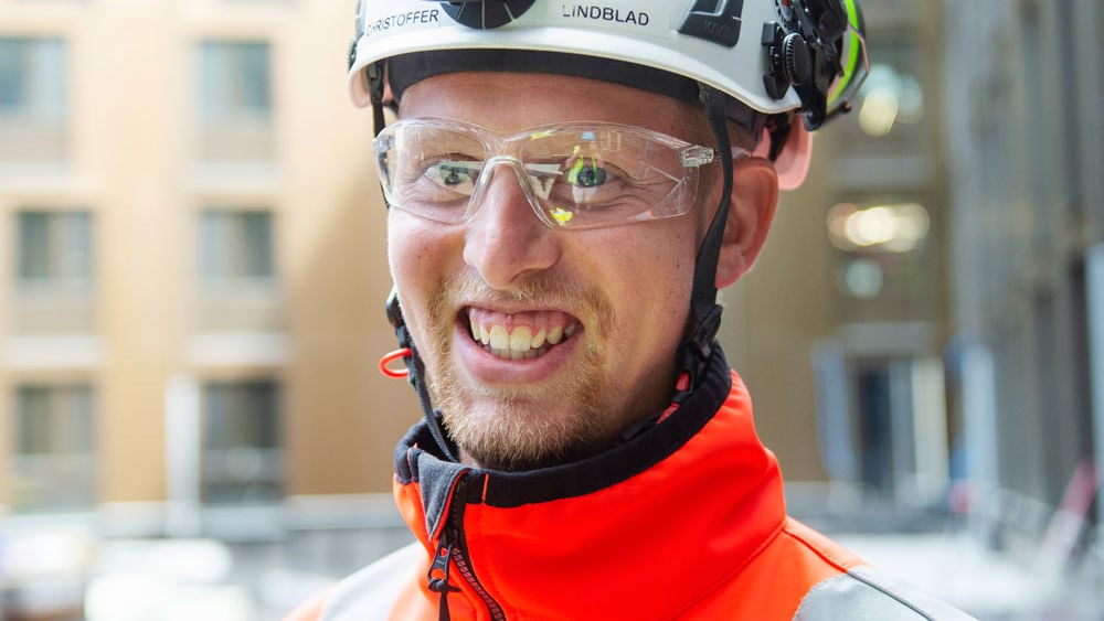 Foto av Veidekkes medarbetare Christoffer Lindblad. Står leende i varselkläder och hjälm.