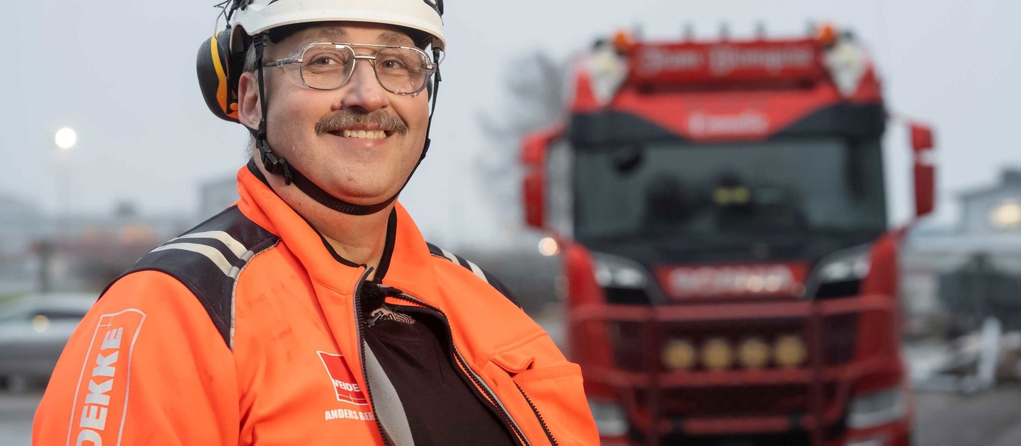 Leende man i orange varseljacka och hjälm -  Anders Berntsson, arbetschef för Veidekke Grundläggning SydVäst,