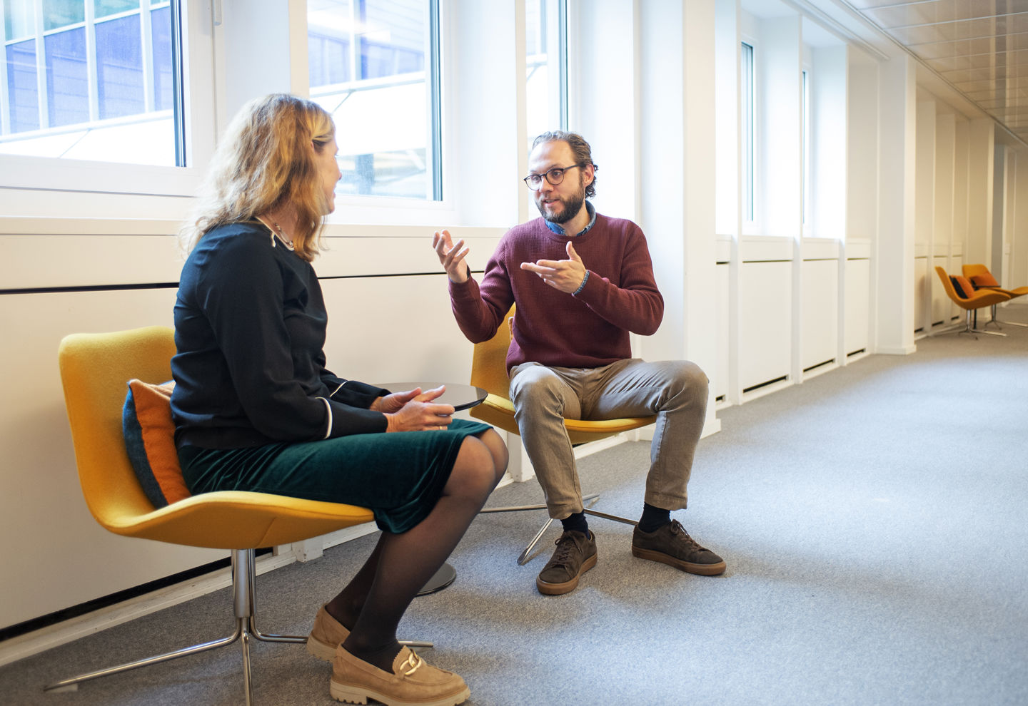 Två personer sitter i fåtöljer och pratar.