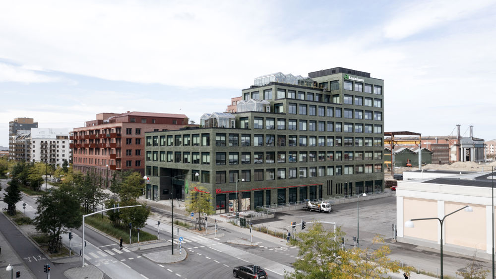 Foto på kvarteret Triton i Malmö med mörkgrå stenbyggnad och ljusröd byggnad vid flerfilig stadsgata. 