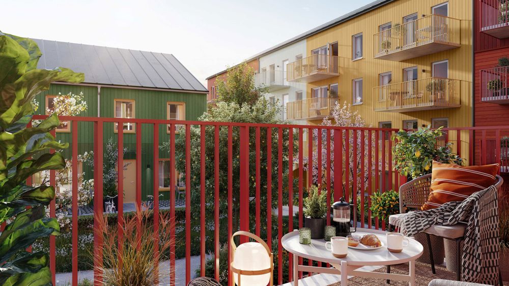 Utsikt från ombonad balkong mot innergård med färgglada flervåningshus - Brf Bolero