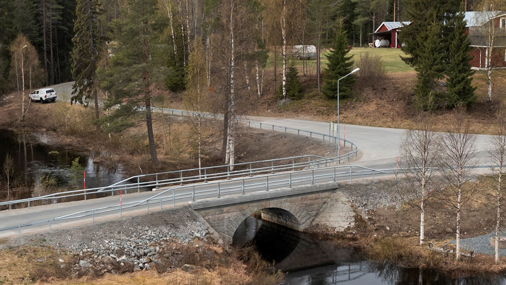 Stenbro över Bjurselebäcken med skog i bakgrunden.