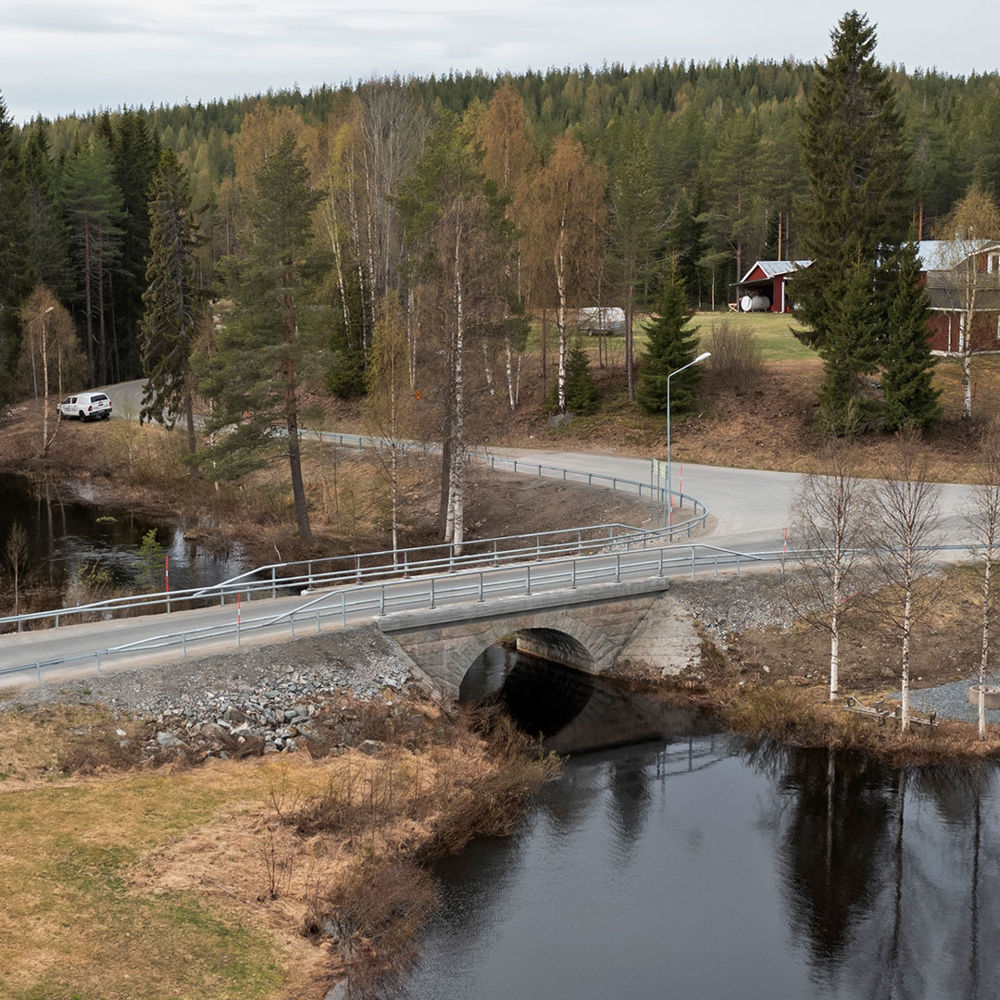 Stenbro över Bjurselebäcken med skog i bakgrunden.