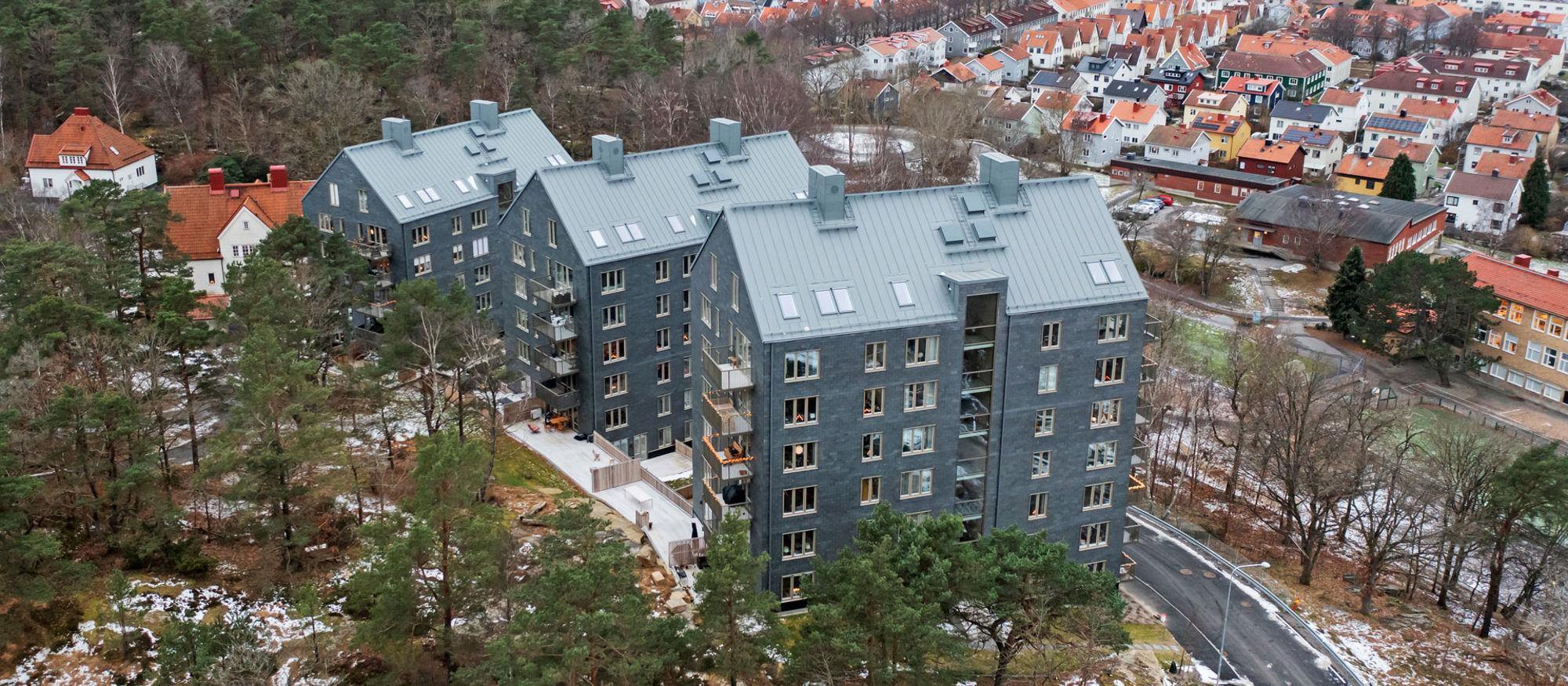 Foto av de tre huskropparna klädda i skiffer som bildar bostadsrätterna Kattugglan.