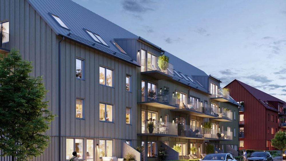 Grått trevåningshus med träpanel och mysiga balkonger - Brf Aroma