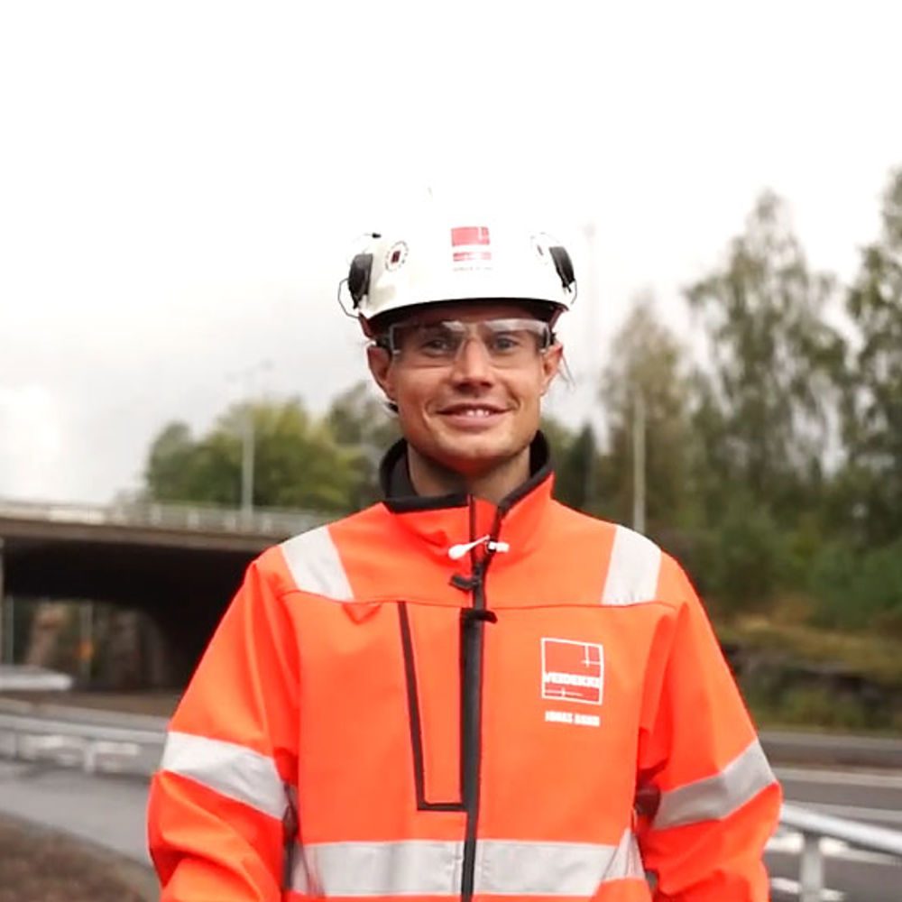 Foto av Veidekkes medarbetare Jonas Bond. Står leende i varselkläder och hjälm.