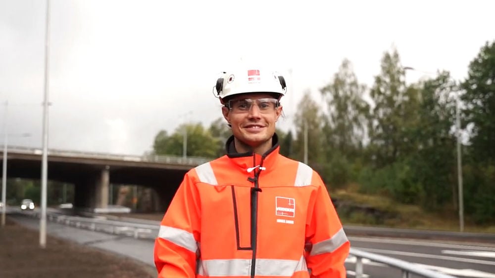 Foto av Veidekkes medarbetare Jonas Bond. Står leende i varselkläder och hjälm.