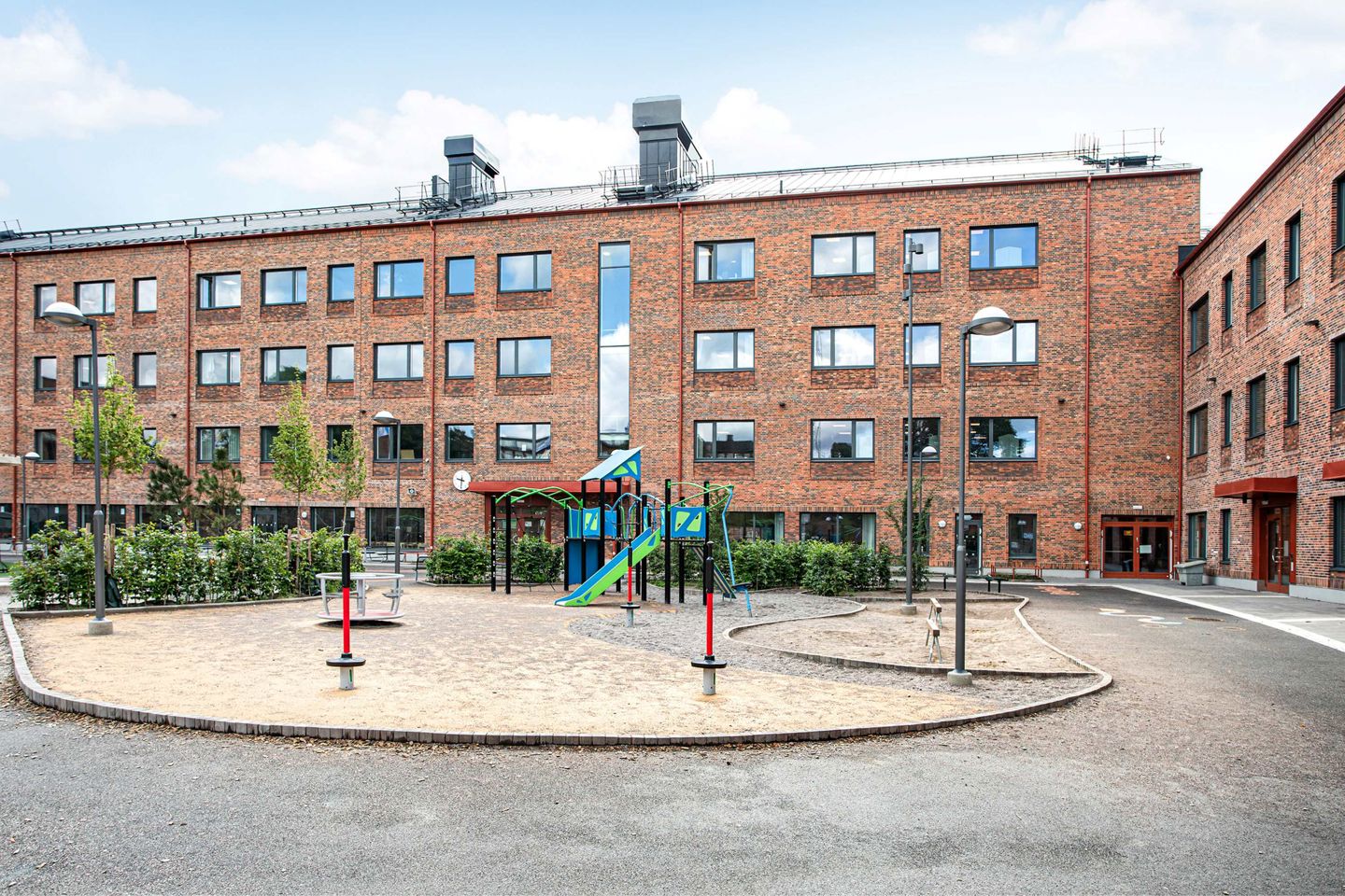 Klätterställning framför Tellus skola med rödbrun tegelfasad