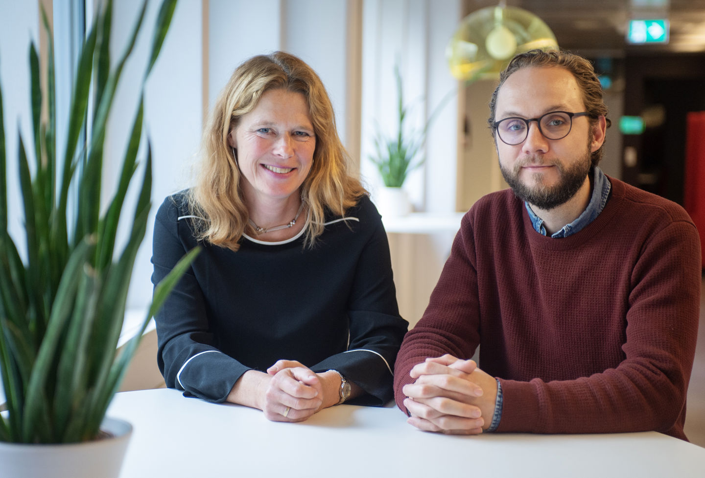 Foto av två leende personer sittandes vid ett bord.