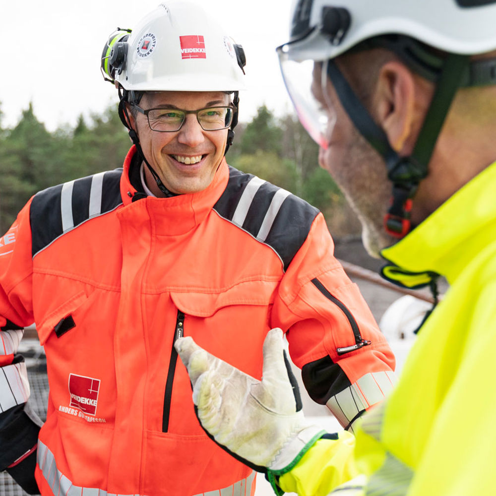 Man står leende och pratar med en kollega.