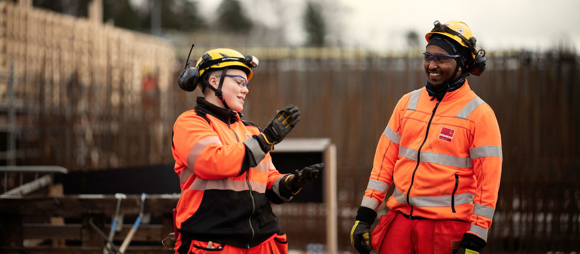 Två personer pratar med varandra på en byggarbetsplats.