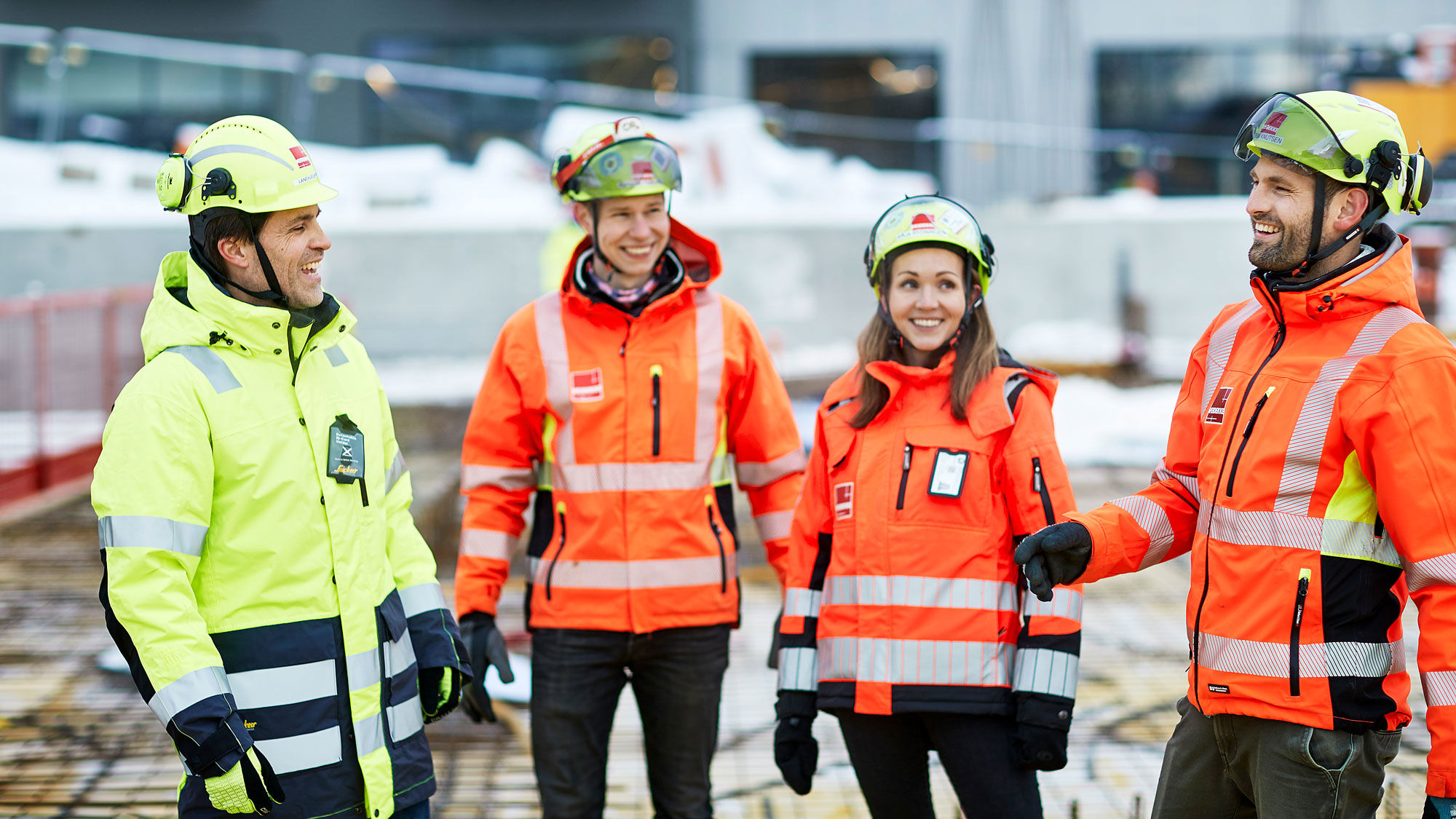 Fyra glada byggjobbare i skyddsjackor
