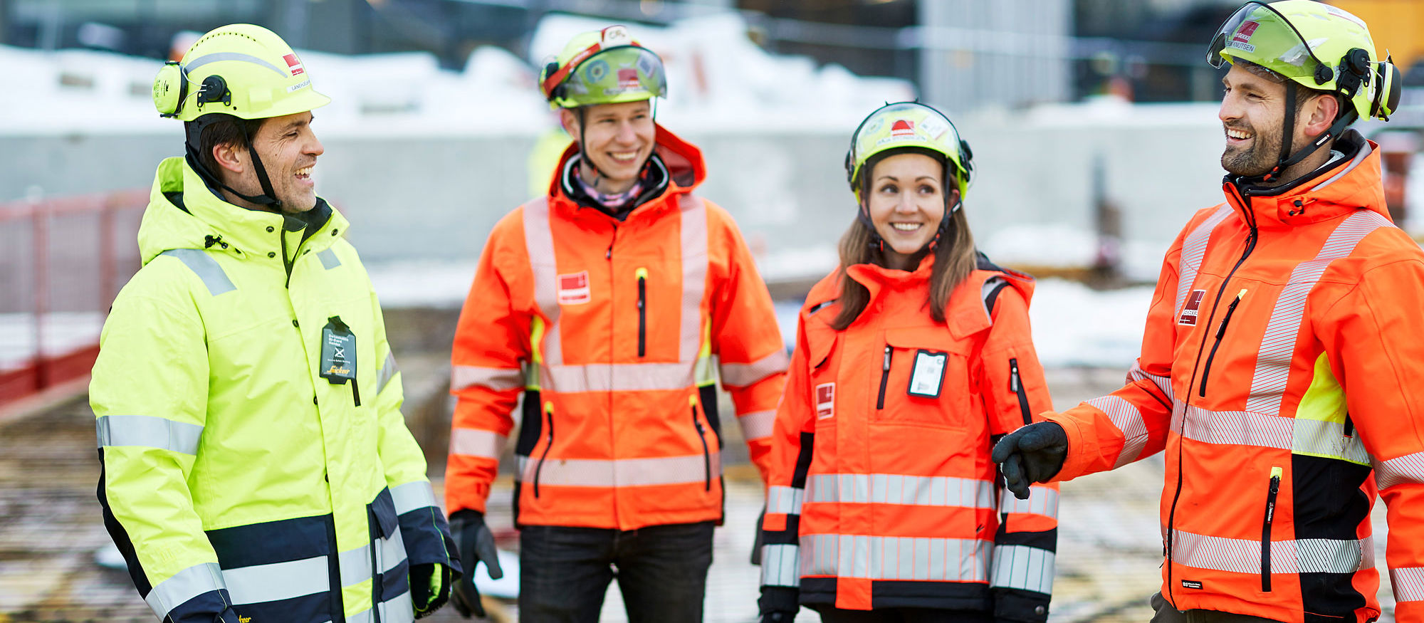 Fyra glada byggjobbare i skyddsjackor