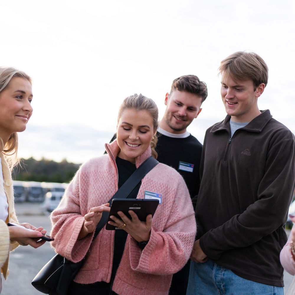 Fem personer diskuterar kring någon som visas på en ipad.