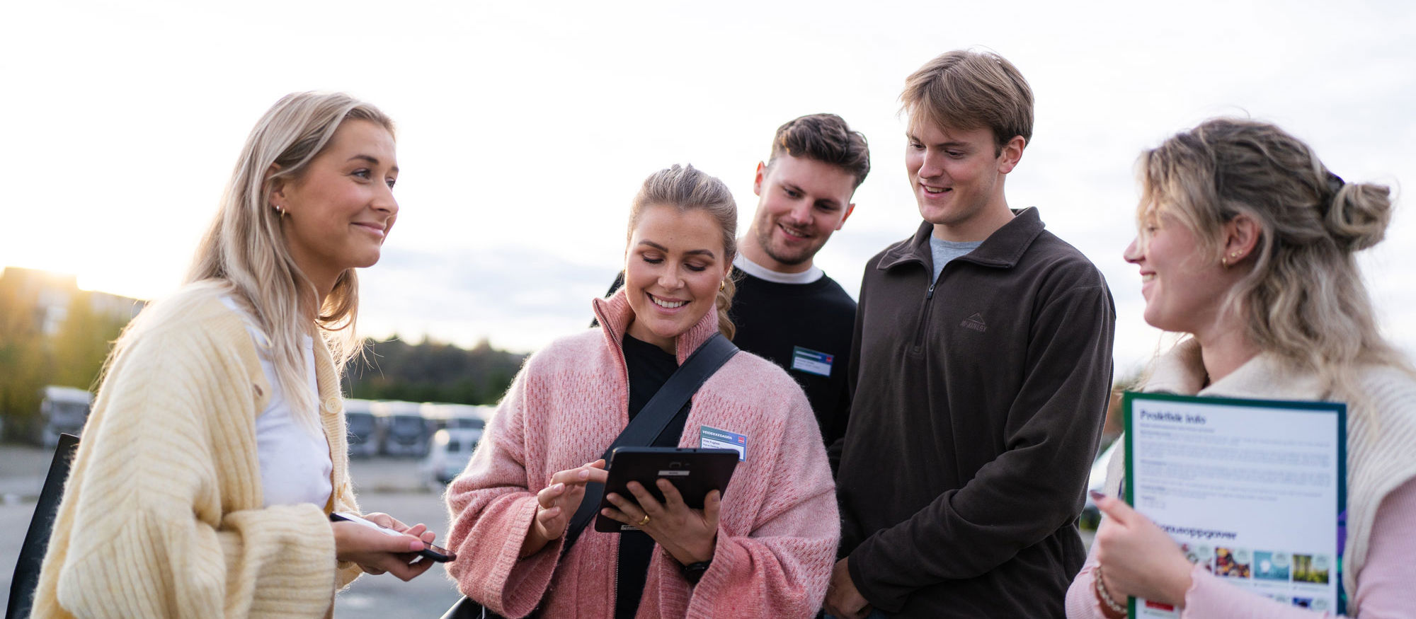Fem personer diskuterar kring någon som visas på en ipad.