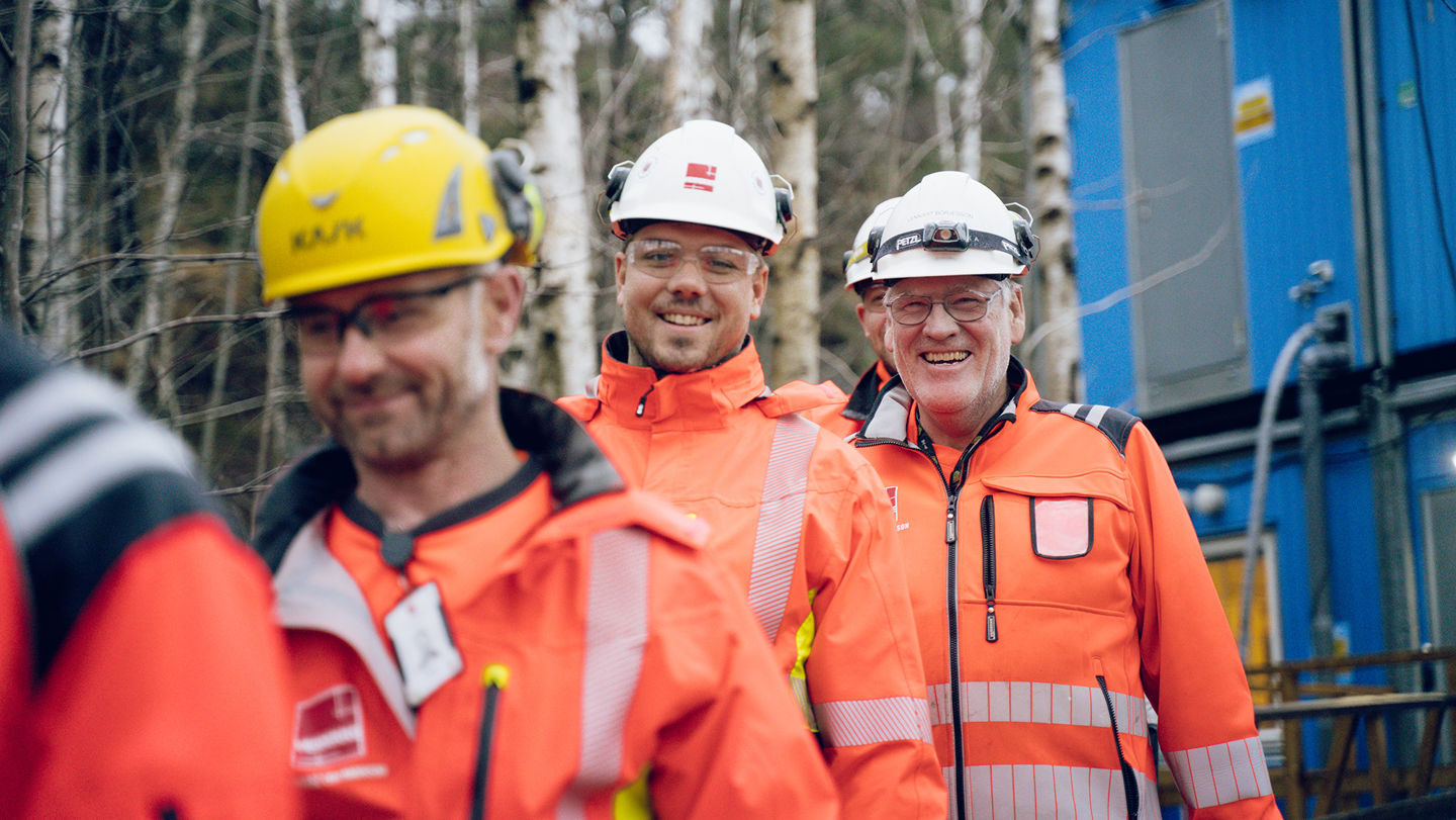 Glada byggarbetare framför en container