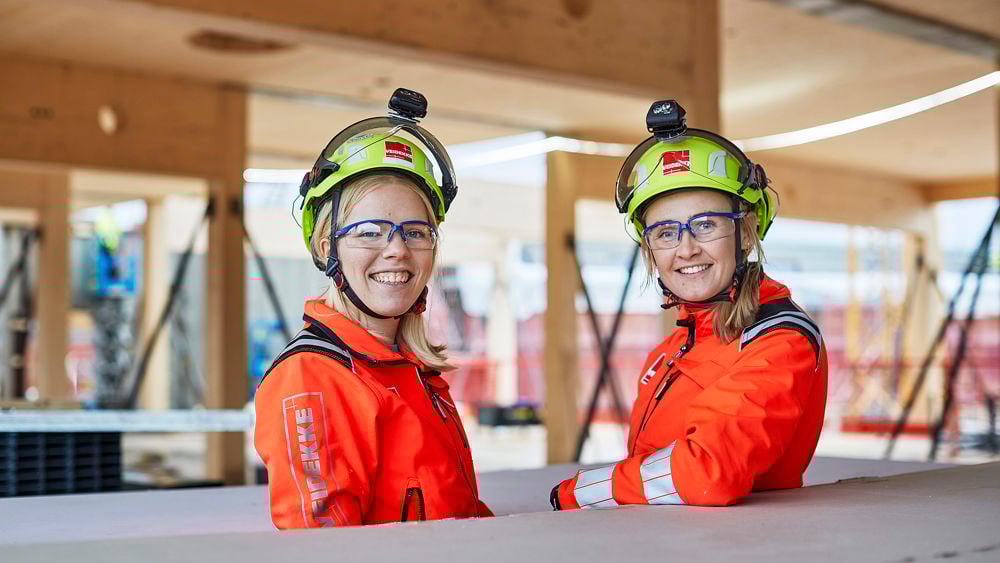 Två glada kvinnliga byggjobbare på ett byggprojekt.