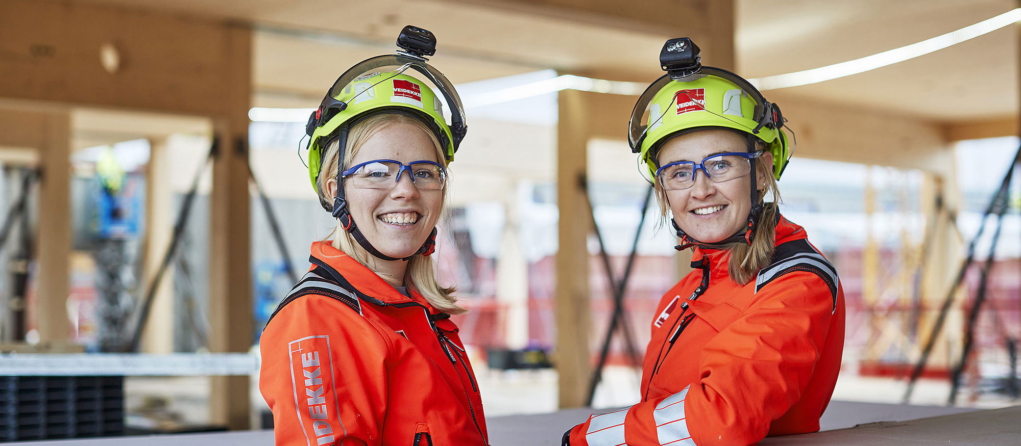 Två glada kvinnliga byggjobbare på ett byggprojekt.