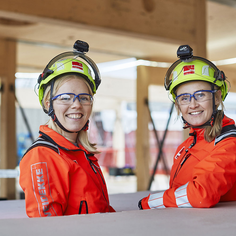 Två glada kvinnliga byggjobbare på ett byggprojekt.