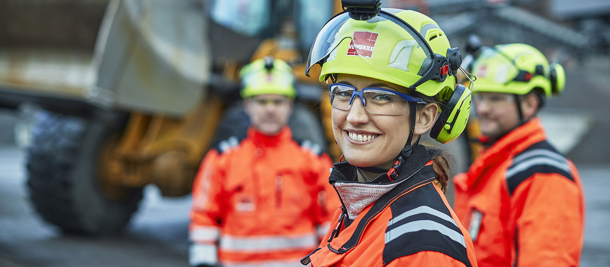 Byggarbetare, en kvinna i förgrunden med män i bakgrunden