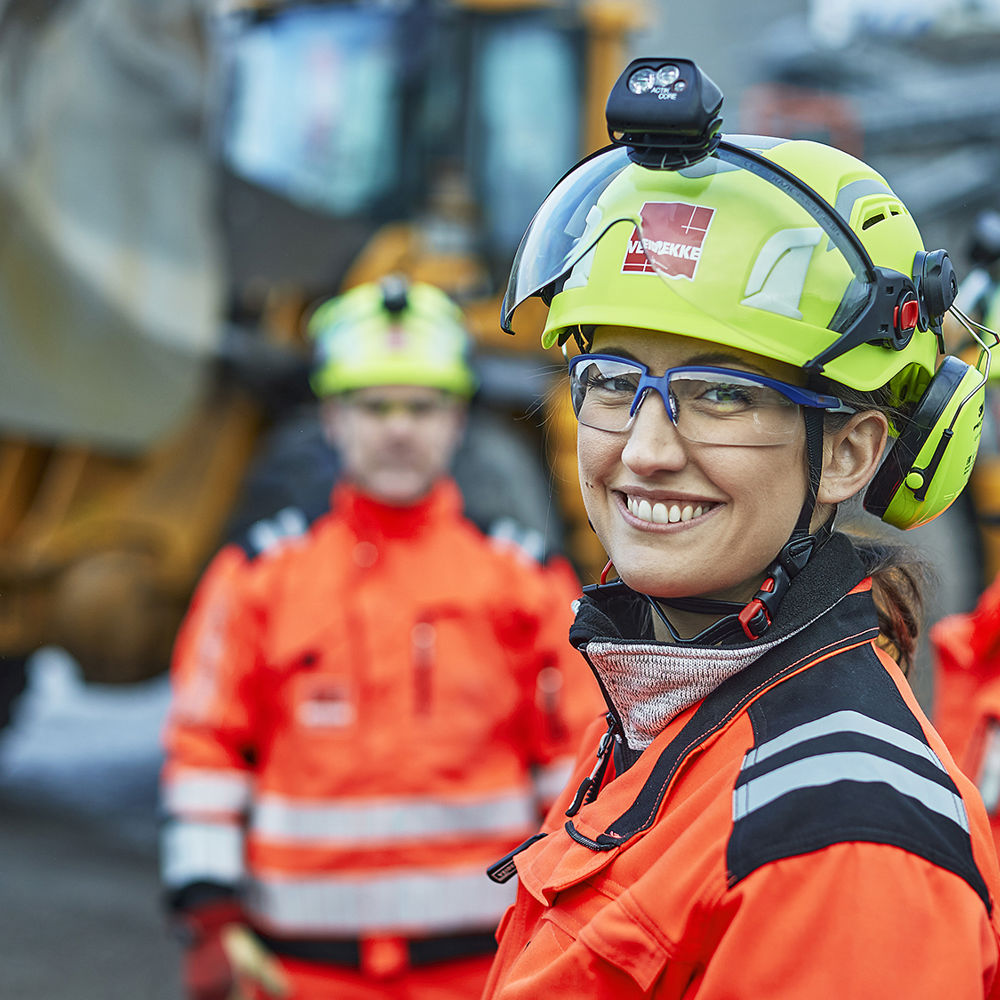 Byggarbetare, en kvinna i förgrunden med män i bakgrunden