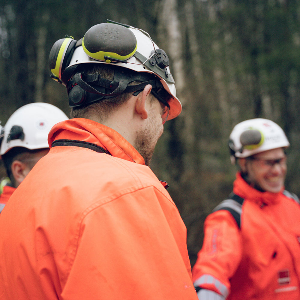 Tre byggarbetare framför en skog