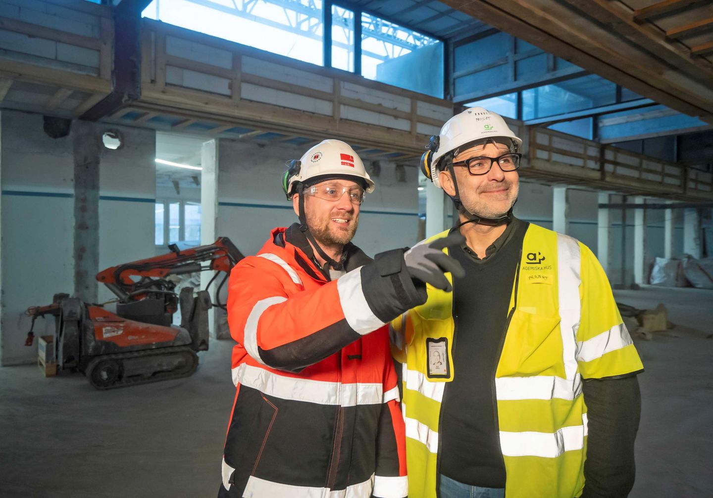 Två män i skyddskläder inomhus i ett byggprojekt: Anders Hogander och Martin Dahlberg